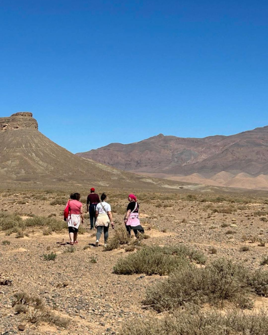 Petit groupe marchant dans le désert marocain face aux montagnes.