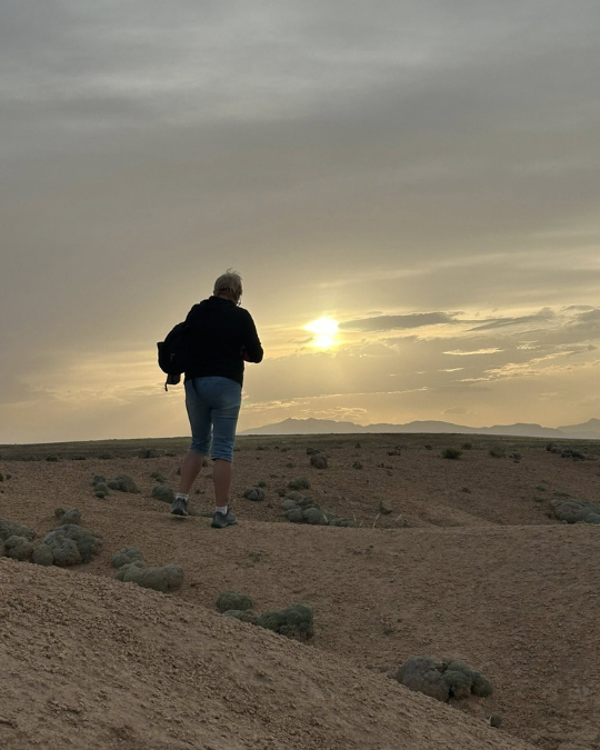 Femme marchant seule dans le désert au coucher du soleil.