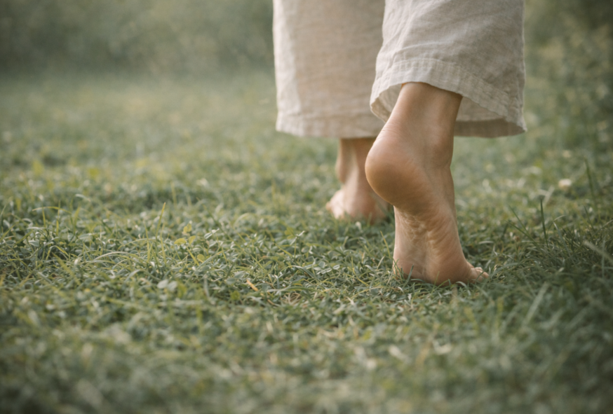Pieds nus marchant lentement dans l’herbe, vus de derrière, symbolisant l’ancrage.