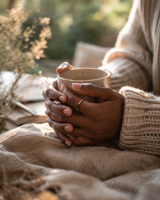 Gros plan sur des mains tenant une tasse dans un moment calme avec lumière naturelle